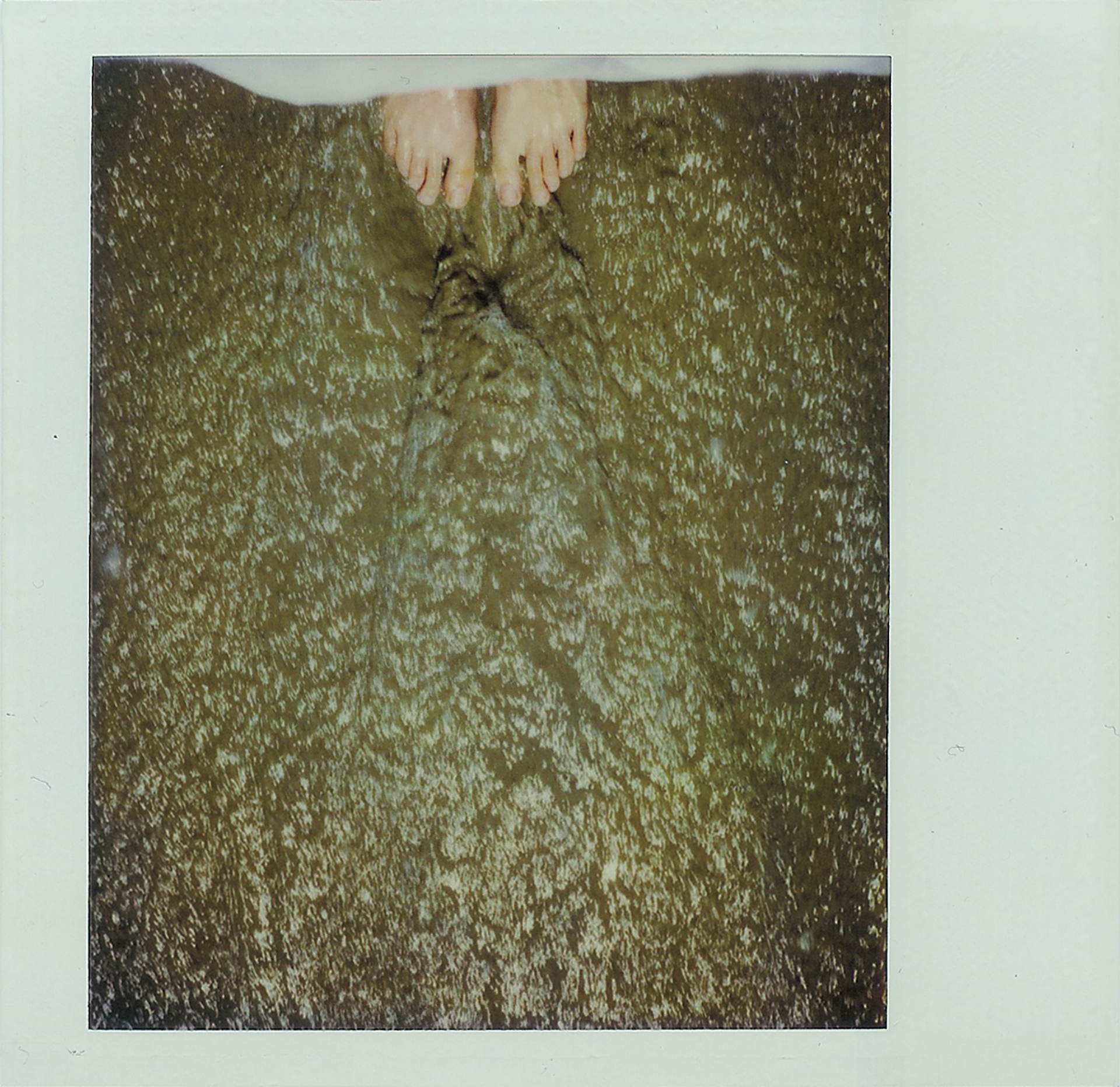 Polaroid, looking down at feet in water, waves, tide pulling the sand away from under barefeet