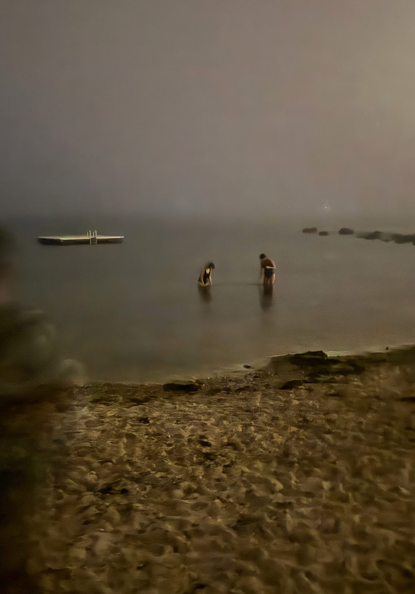 Photograph of two figures wading in the waves, girls in water, searching, night, looking in the sea, disappearing figures, dreamlike landscape